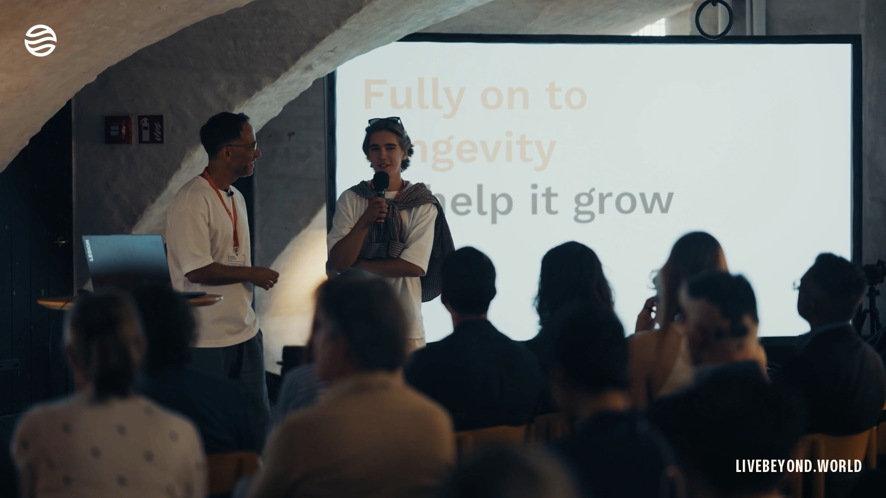 Aleksander auf der Bühne der ARDD, Kopenhagen, September 2024. Auf der Folie hinter ihm steht: help it grow.