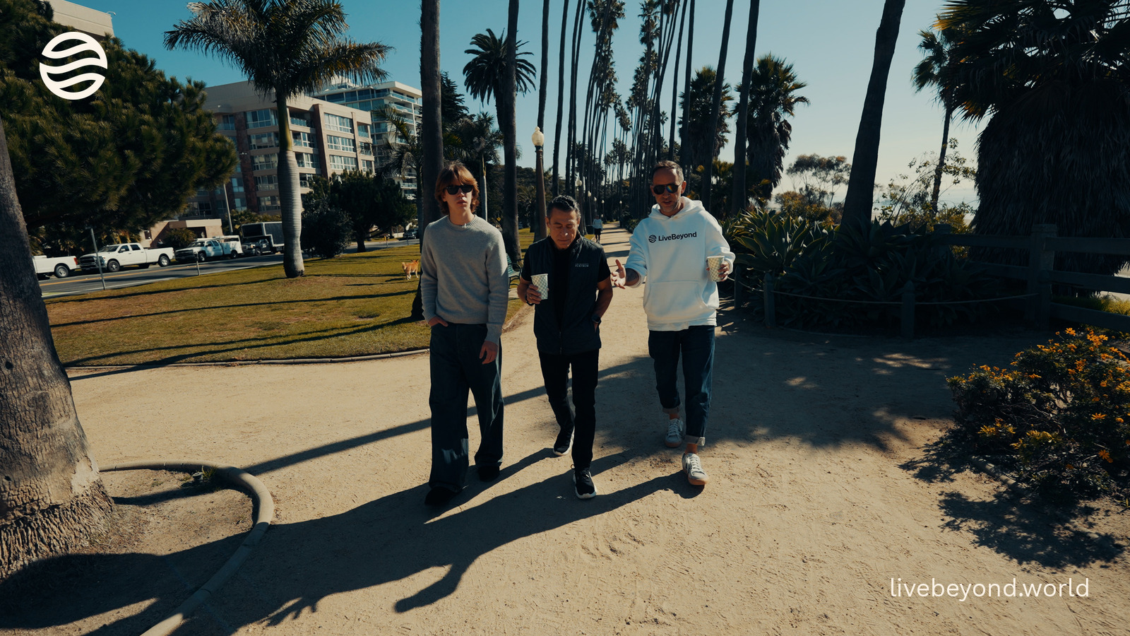 Alek, Peter Diamandis and Marek walking together under the palm trees by the ocean in Santa Monica.