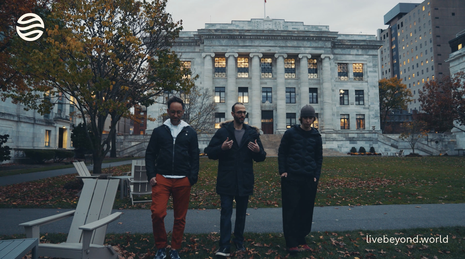 Mahdi Moqri walking and talking with Marek and Alek in front of a marble building at Harvard Medical School.