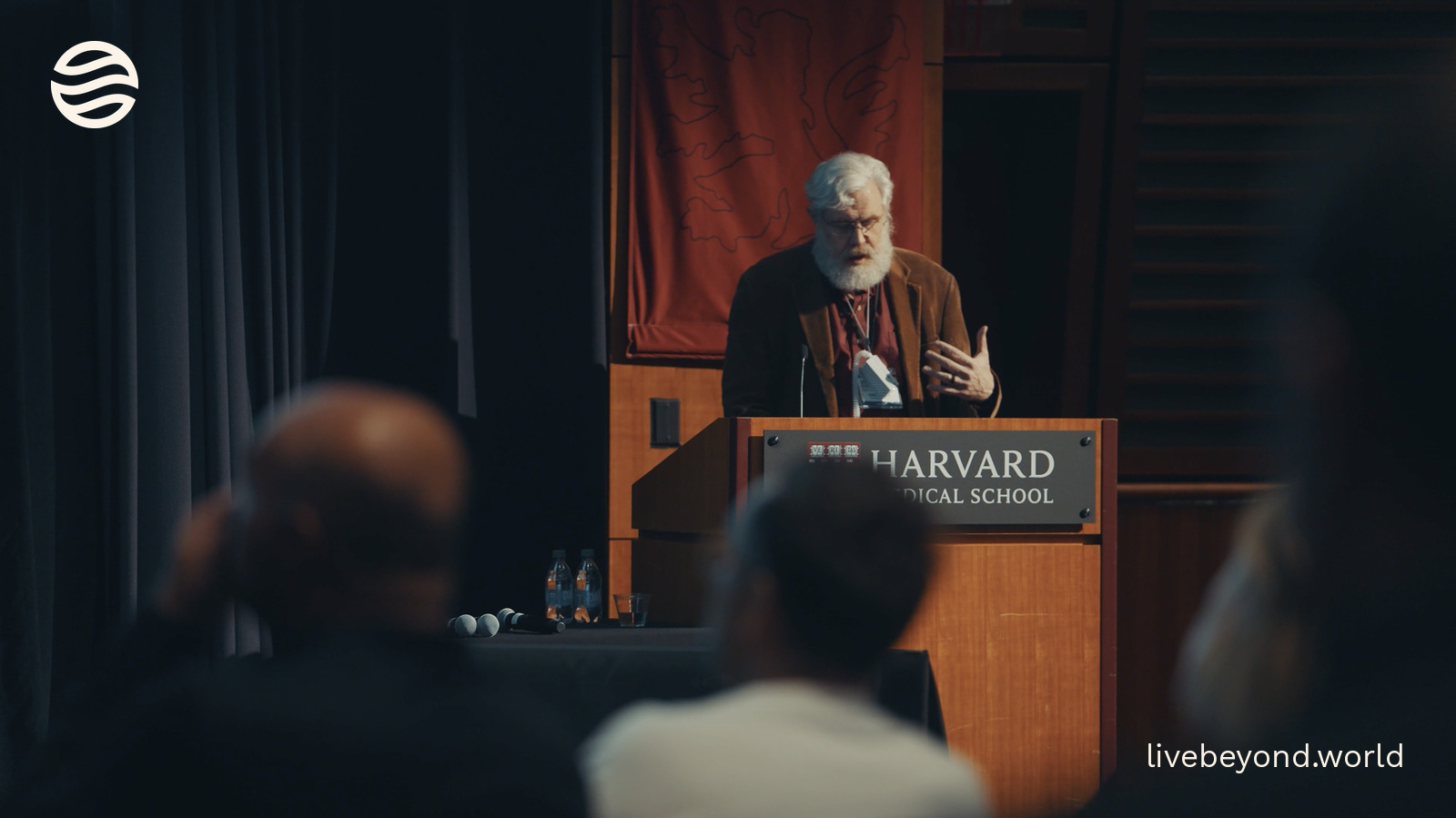 George Church at a Harvard Medical School lectern, the audience in front of him.