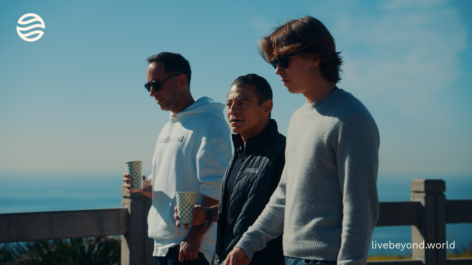 Marek, Peter Diamandis and Alek standing by a railing above the ocean, holding coffee cups.