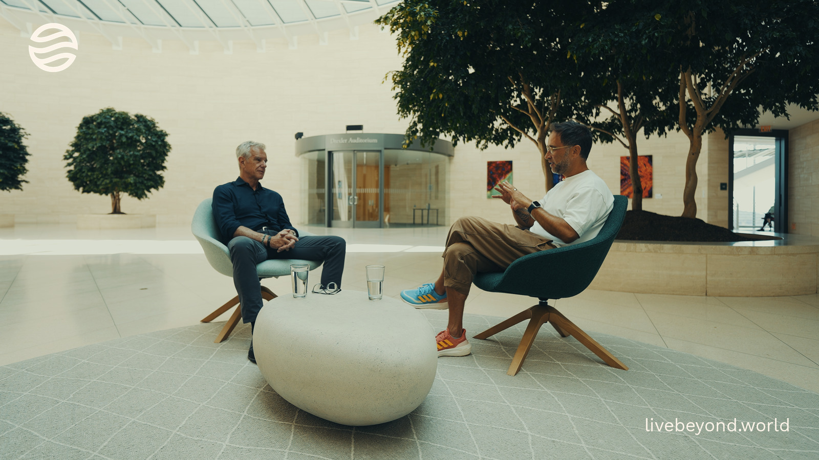 Marek and Eric Verdin talking in armchairs in the bright atrium of the Buck Institute.