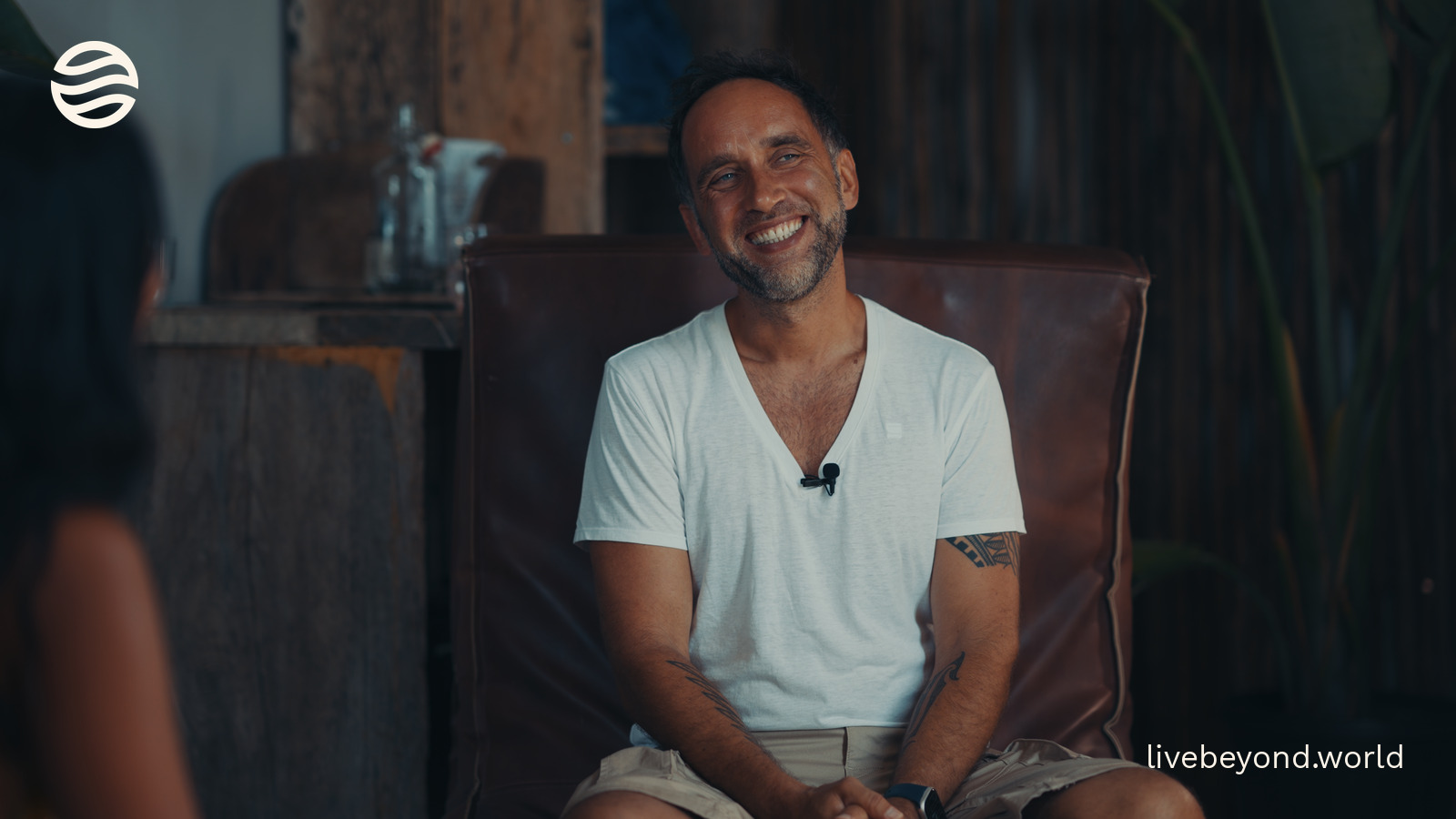 Marek smiling in a leather armchair during an interview.