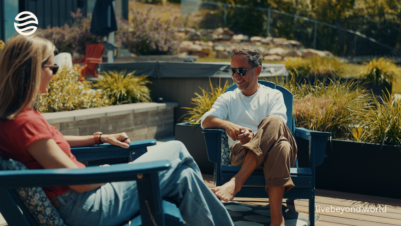Amy Killen and Marek sitting in blue deck chairs on a terrace, mountains behind them.
