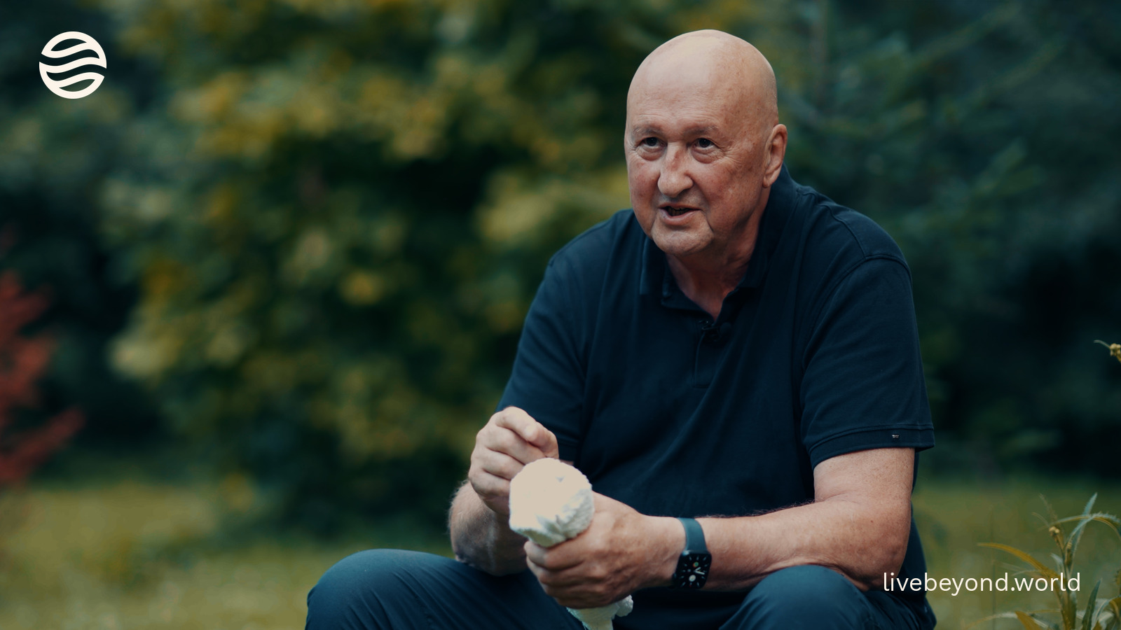 John Davies explaining, sitting in a green wood.