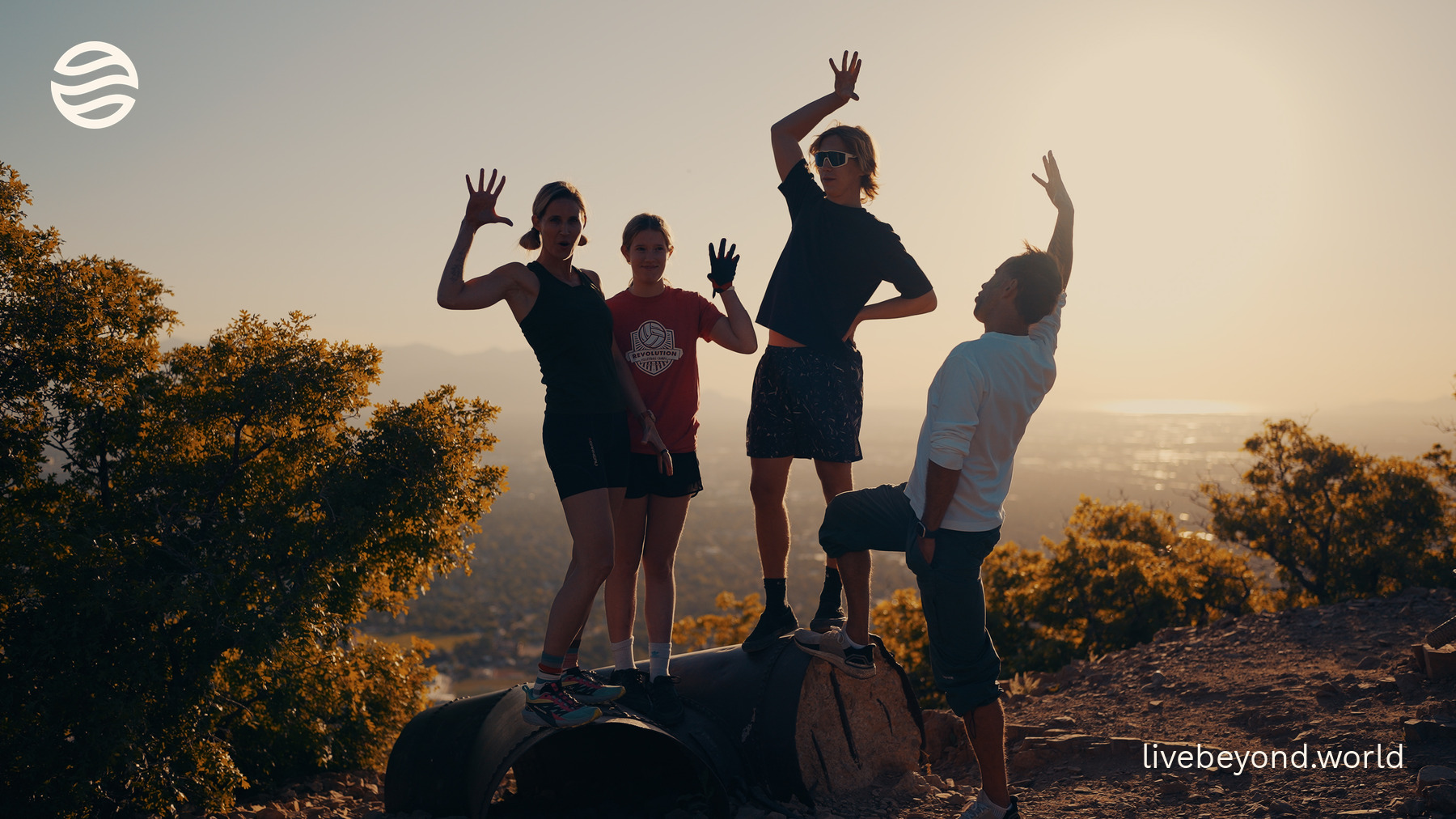 Amy Killen, her family, Marek and Alek jumping and waving on a hilltop above Salt Lake City at sunset.