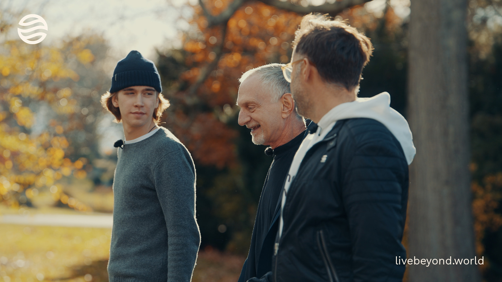 Robert Waldinger laughing with Marek and Alek among autumn trees.