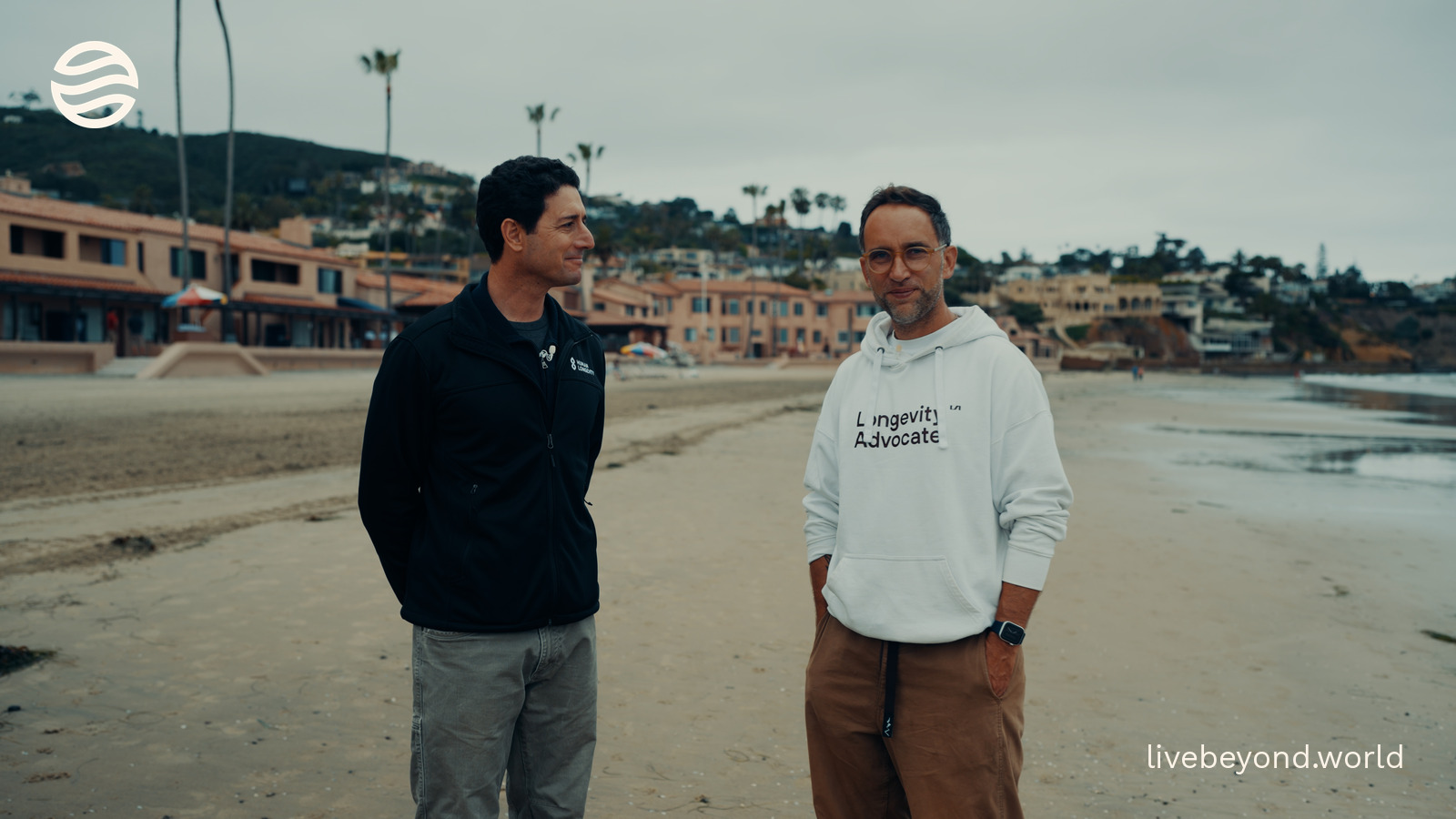 Eric Dinenberg and Marek standing on a wide beach in San Diego, talking.