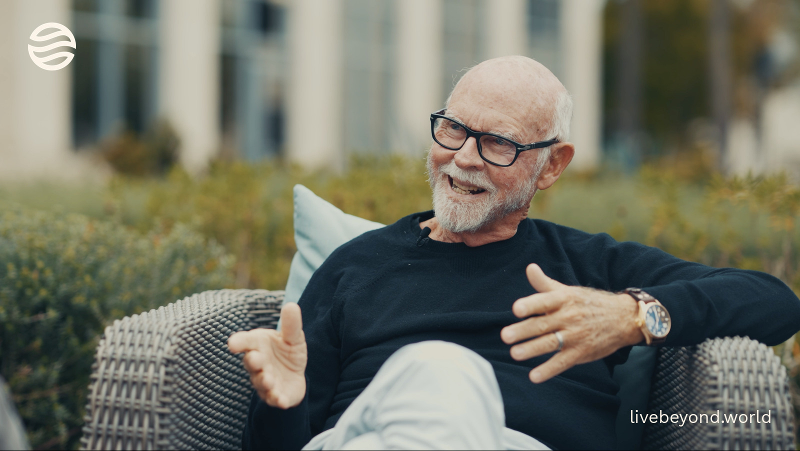 Craig Venter smiling in a wicker chair outdoors.