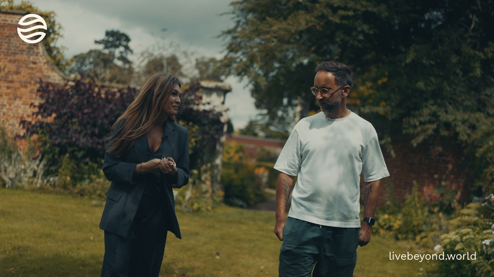 Staša Stanković and Marek walking side by side through a garden.