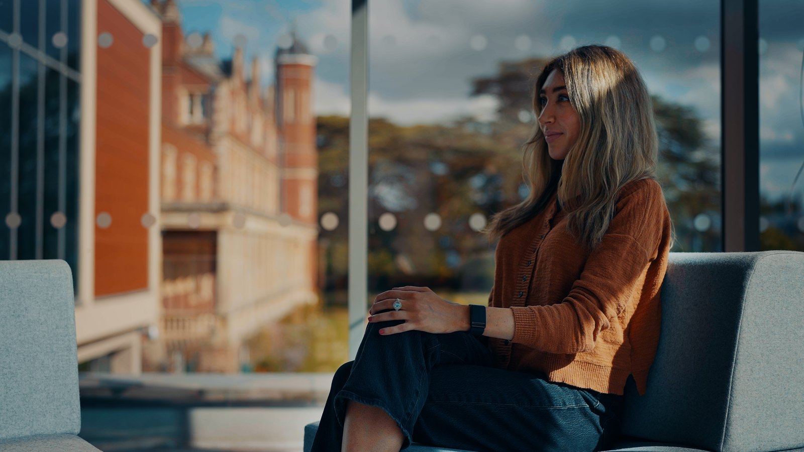 Breanna Deutsch seated at the Babraham Institute, with the Cambridge campus behind