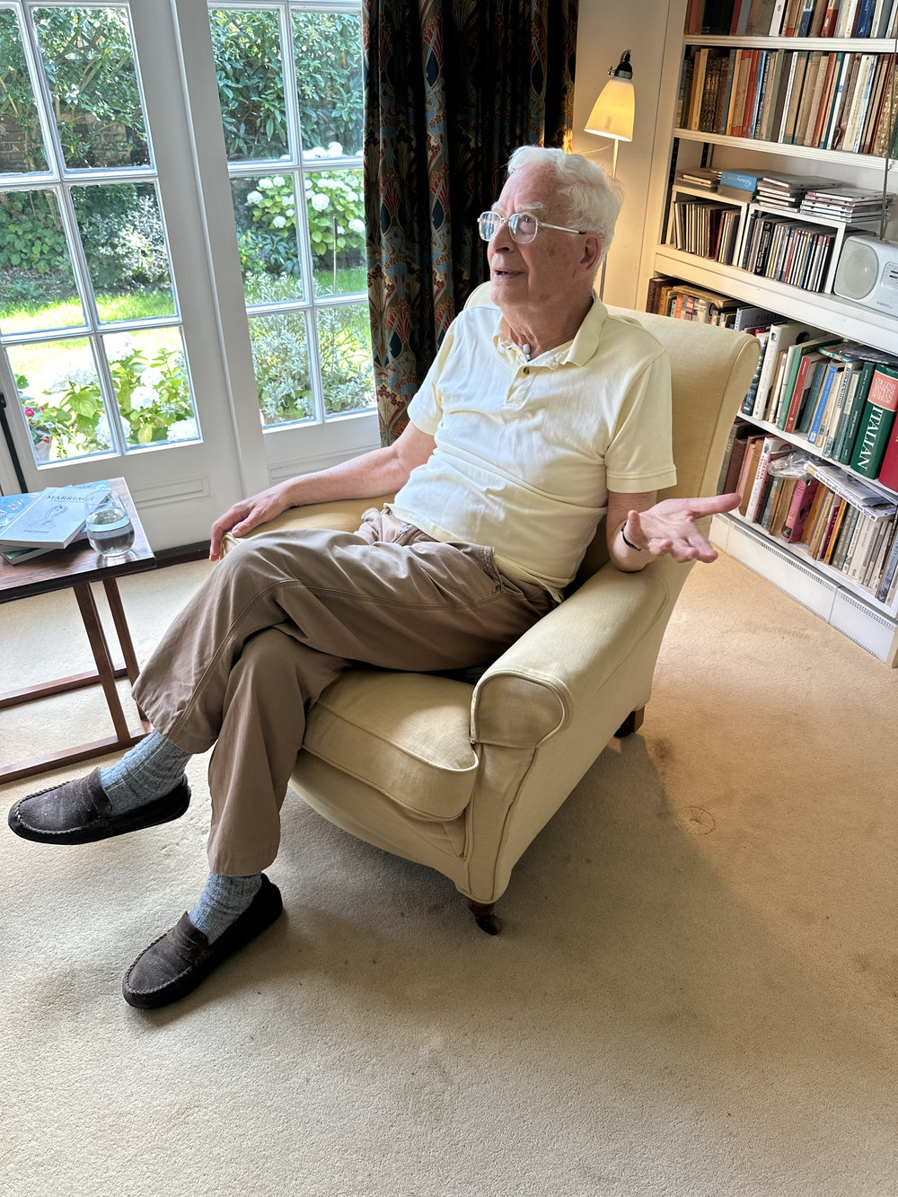 Sir Christopher Ball in his armchair, bookshelves behind him, at his home in Oxford