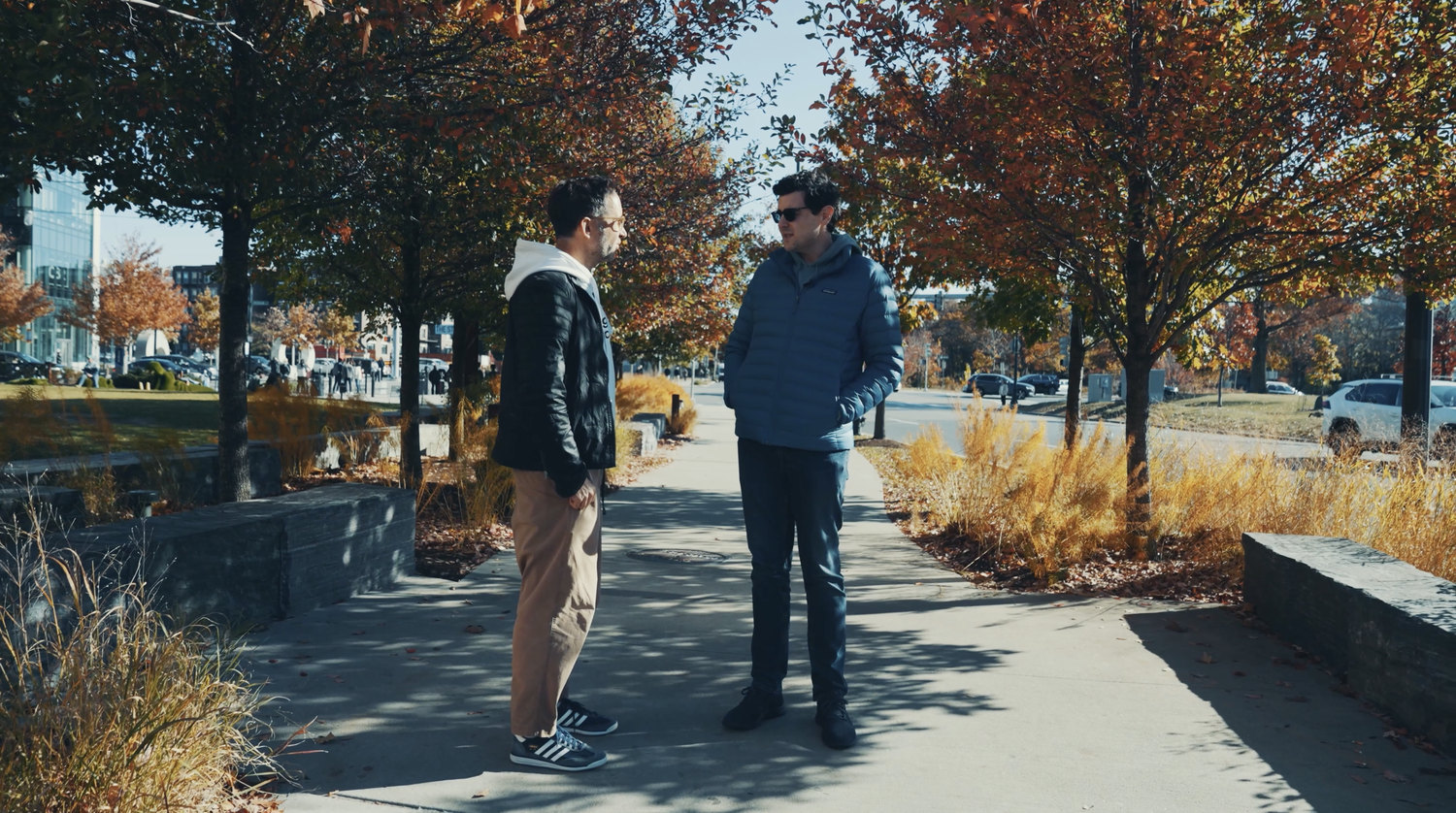 Jesse Poganik and Marek Piotrowski talking in a park in Boston, November 2024