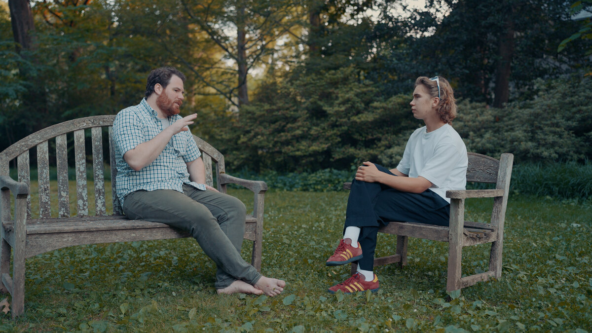 Dane Gobel and Aleksander in conversation on park benches in Washington