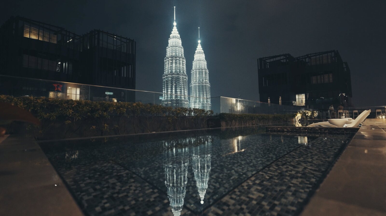 The Petronas Towers at night reflected in a rooftop pool in Kuala Lumpur