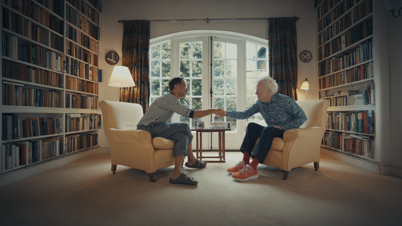 Marek and Sir Muir Gray shaking hands across the two armchairs in the Oxford library