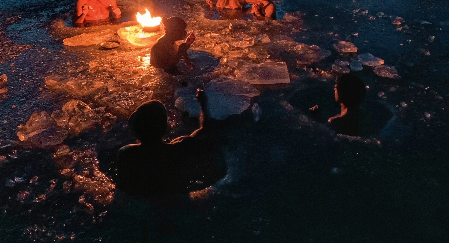 Ron Batuigas ice-bathing by firelight with the community at dusk