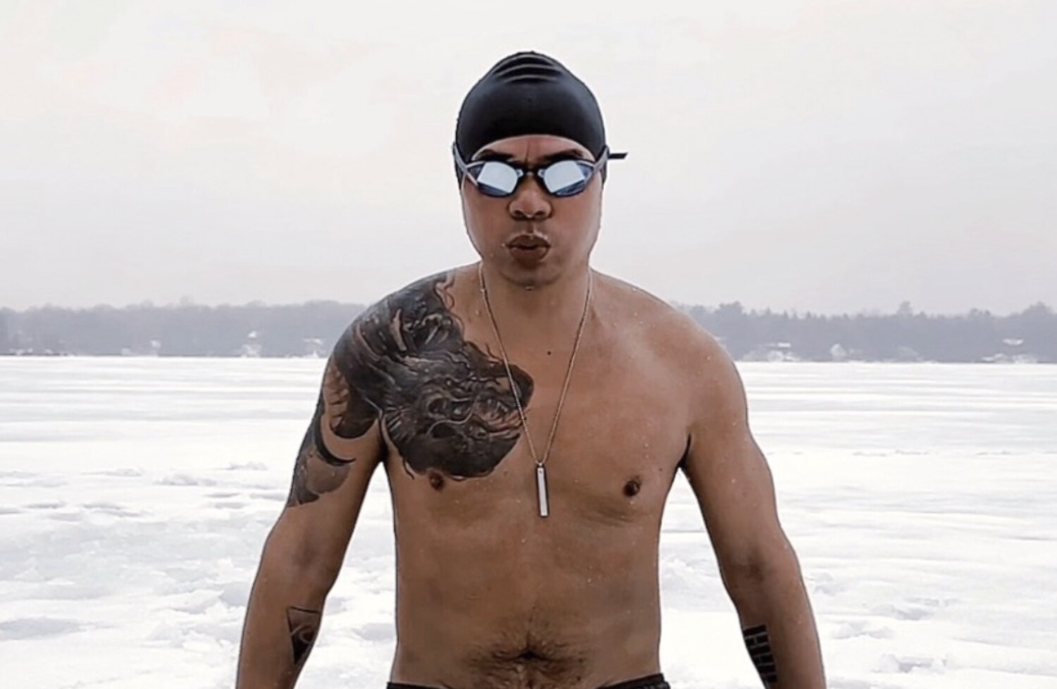 Ron Batuigas standing waist-deep in an ice hole on a frozen lake